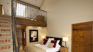Ein Schlafzimmer mit einem Bett, einem Nachttisch, einem Holzschrank, einem Spiegel und einer Treppe.