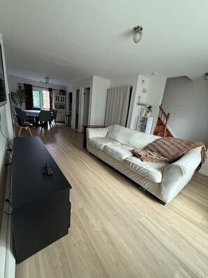 A modern living room with a sofa, a coffee table, and a dining area with chairs and a table.