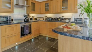 Une cuisine moderne avec des meubles en bois, un four encastré, un four à micro-ondes et un plan de travail en granit.