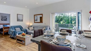 Ein modernes Wohnzimmer mit Essbereich, einer Sofagarnitur und Blick ins Freie.