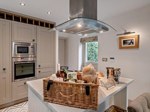 A modern kitchen with built-in appliances, a central island, and a view of greenery outside. - 2 Bed in Scarborough (oc-g0179) (Staintondale)
