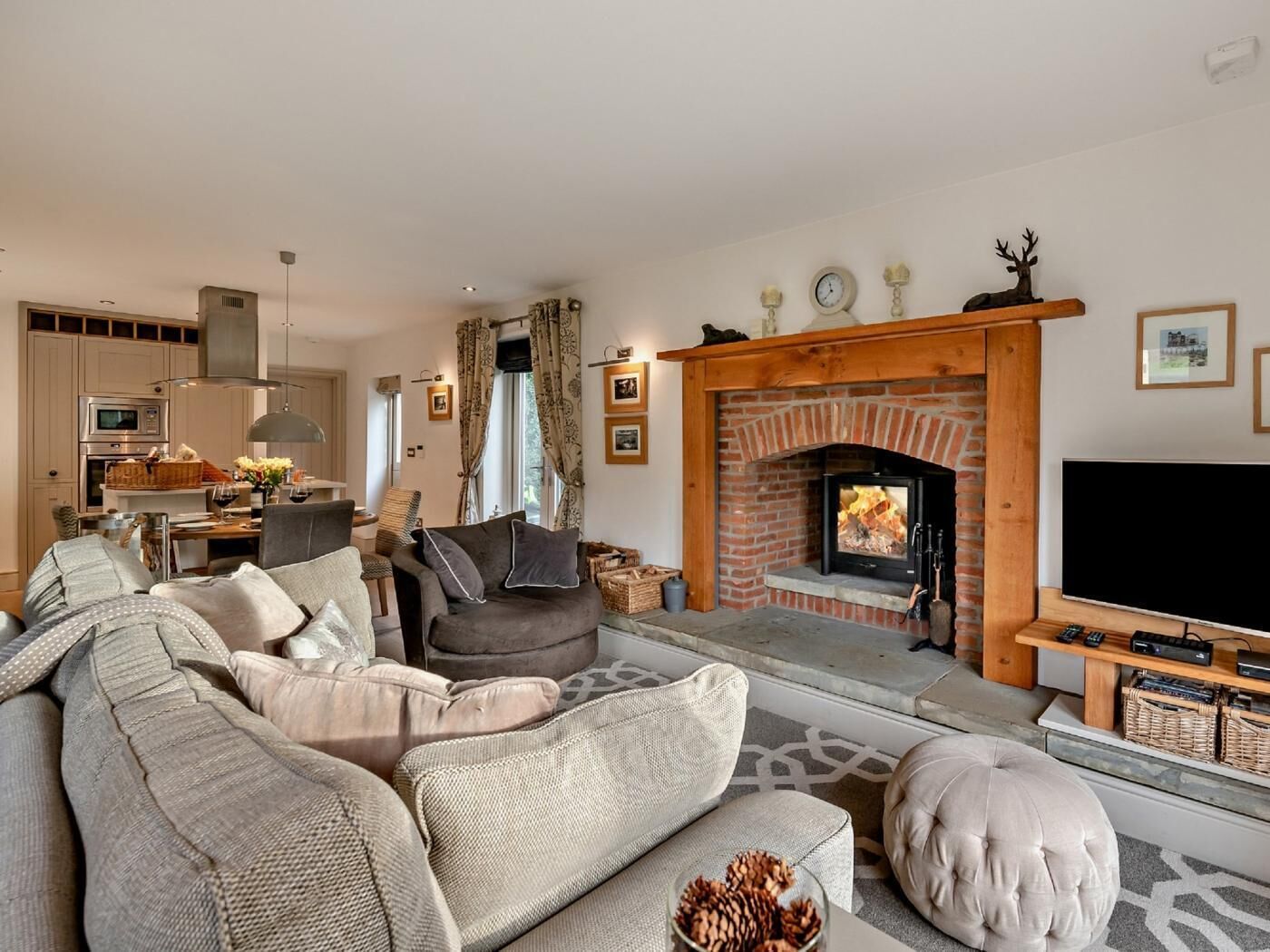A living room with a fireplace, sofa, television, and kitchen area.