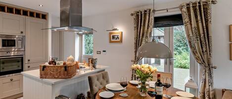 Una cucina moderna con elettrodomestici integrati, un'area pranzo con tavolo rotondo e vista sul verde circostante.