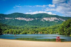 A beach with a lifeguard chair, a lake, and forested mountains in the background. - Stunning, huge 5 bdrm log home- Canoe/firepi!t/pet (Lake Lure)