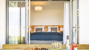 Ein Schlafzimmer mit einem Bett, einem Nachttisch mit Lampe und Blick durch eine Glastür.