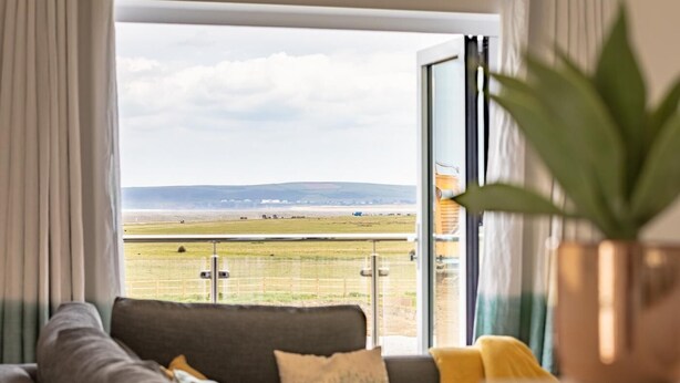 Ein Balkon mit Blick auf ein Wiesenfeld und sanfte Hügel in der Ferne.