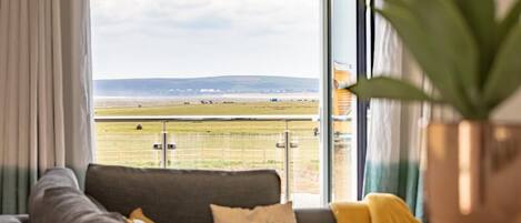 A balcony with a view of a grassy field and distant hills.
