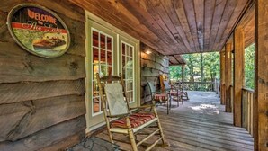 Une cabane en bois avec un porche, une pancarte de bienvenue et des sièges à l’extérieur.