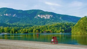 A lake with a red lifeguard stand on the shore, surrounded by green hills and a clear sky. - Private LogHome/ HotTub/Lake Lure/pet (Lake Lure)