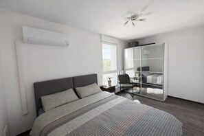 Een slaapkamer met een bed, een stoel, een garderobe en een plafondventilator.