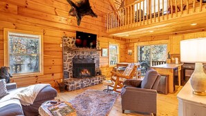 A cozy cabin interior with a stone fireplace, wooden furniture, and a balcony. - Huge River/Mountain Views!3story log/canoes/ pet (Lake Lure)