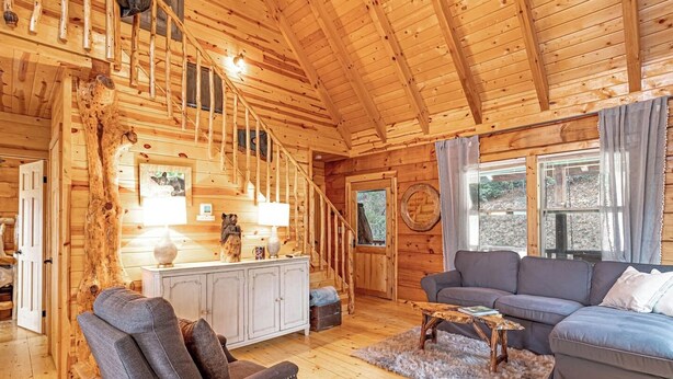 A wooden cabin interior with a staircase, a sofa, a coffee table, and a dining area. - Huge River/Mountain Views!3story log/canoes/ pet (Lake Lure)