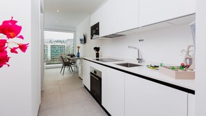 Eine moderne Küche mit weißen Schränken, einer schwarzen Arbeitsplatte, einem Einbauofen, einem Spülbecken und einem Fenster mit Blick auf die Stadt.