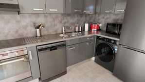 Cozinha moderna com eletrodomésticos de aço inoxidável, incluindo lava-louças, forno e máquina de lavar roupa.