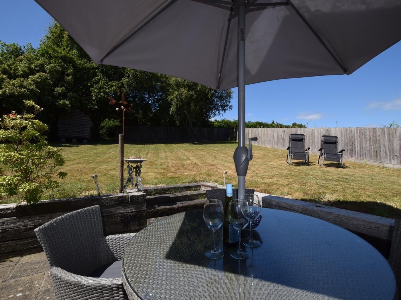 An outdoor patio with a round table, chairs, and a large umbrella.