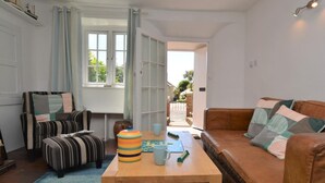 Een woonkamer met een gestreepte bank, een houten bijzettafeltje en een gestreepte poef.