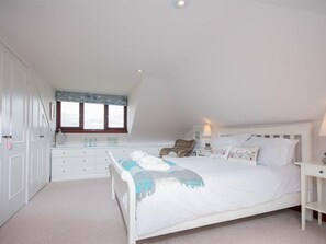 A bedroom with a bed, bedside tables, a window, a wardrobe, and a desk. - 4 Bed in Swanage (oc-dc020) (Studland)