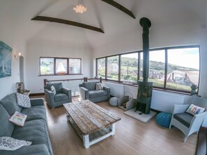 A spacious living room with a large window, a fireplace, and a view of the countryside. - 4 Bed in Swanage (oc-dc020) (Studland)