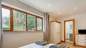 A bedroom with a large bed, a wardrobe, a television, and a bathroom visible through an open door. - 3 Bed in Wareham (oc-dc157) (Stoborough)