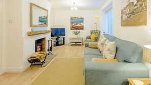 Ein Wohnzimmer mit Kamin, Fernseher, einer Couch und Kunstwerken an den Wänden.