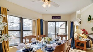Ein Esszimmer mit Tisch für vier Personen, großen Fenstern und einem Deckenventilator.