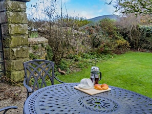 A round metal table with a metal chair, a bottle of iced tea, a plate with a croissant, and a cup. - 2 Bed in Lamplugh (oc-sz418) (Lamplugh)