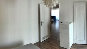 Um quarto com porta branca, armário branco e luminária no teto.