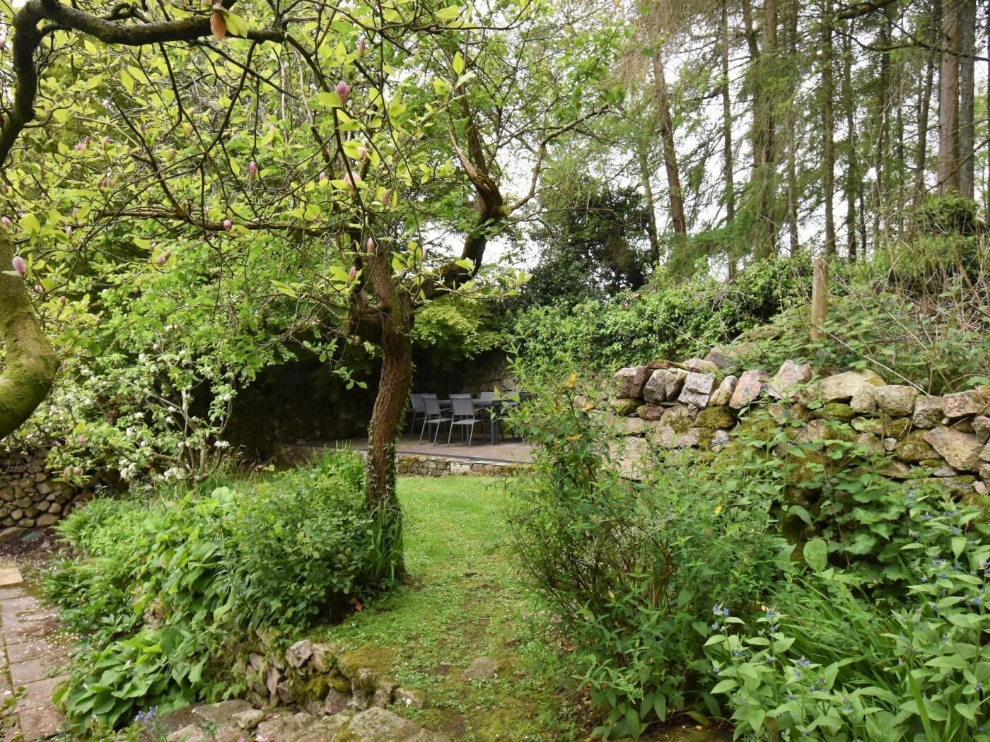 A stone wall, a pathway, and a seating area with chairs.