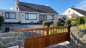 A residential property with a gated entrance, a stone nameplate, and a well-maintained lawn. - 2 Bed in Moelfre (oc-75013) (Moelfre)