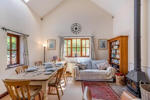 A cozy living room with a dining area, a fireplace, and a large window with curtains.