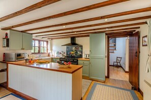 A kitchen with wooden beams, a central island, a stove, and a sink.