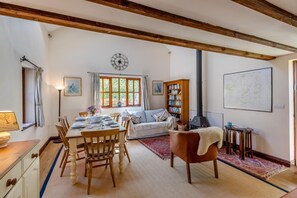 Un comedor con una mesa y sillas de madera, un sofá, una estantería y un mapa en la pared.
