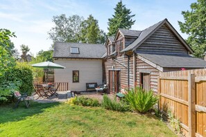 A wooden house with a patio, a table, and a chair.