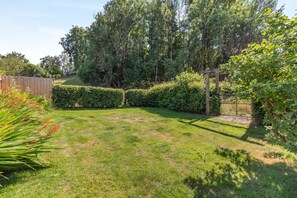 Un jardín bien cuidado con cerca de madera, setos recortados y diversas plantas.