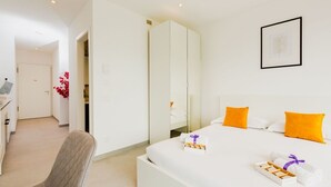 Une chambre d’hôtel comprenant un lit, une table de chevet, une chaise, une armoire et un tableau encadré au mur.