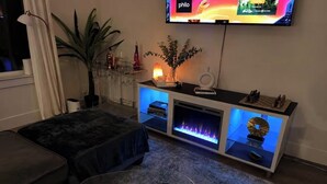 Ett vardagsrum med en TV, en öppen spis och en soffa.