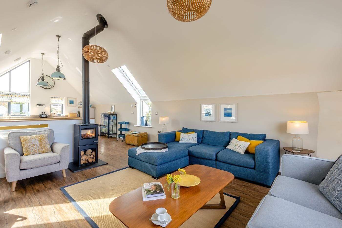 A modern living room with a fireplace, blue sofas, and a wooden coffee table.