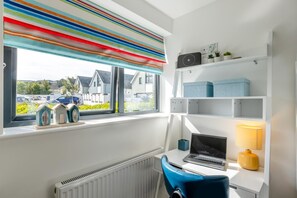 A room with a window, radiator, desk with laptop, chair, and shelves with storage boxes. - 4 Bed in Bideford (oc-75358) (Northam)