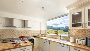 A modern kitchen with a large window, a stove, and a dishwasher. - 12 Bed in Bala (oc-75289) (Llandderfel)