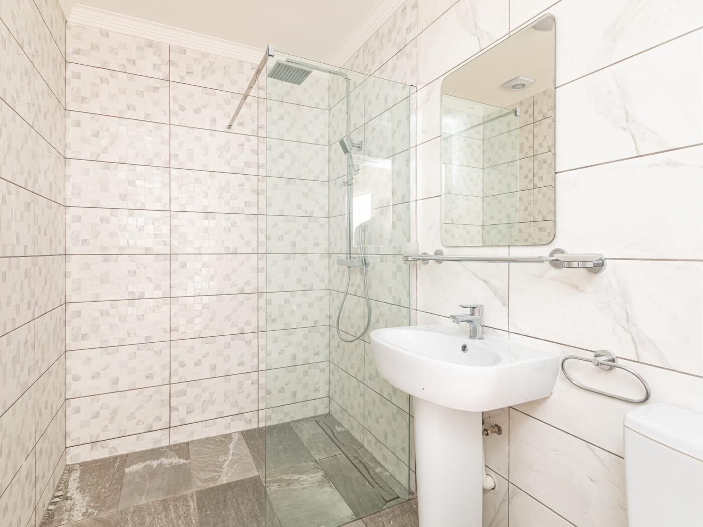 Ein Badezimmer mit Dusche, Waschbecken und Spiegel.