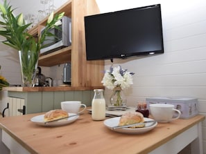 A breakfast setup with two plates of scones, a glass of milk, and a vase of flowers on a wooden table.