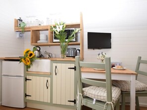 Une cuisine compacte équipée d’un réfrigérateur, de meubles en bois, d’un four à micro-ondes et d’un évier.