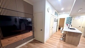 Eine moderne Küche mit integriertem Fernseher, Holzboden und einer zentralen Kochinsel mit Spüle.