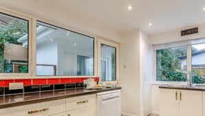Eine moderne Küche mit weißen Schränken, einem Geschirrspüler und einem Fenster mit Blick auf einen Garten.