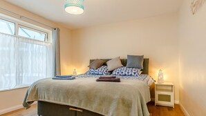 Ein Schlafzimmer mit Bett, Nachttischen, einem Fenster und einer Pendelleuchte.