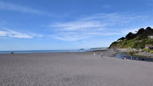 Ein Strand mit blauem Himmel, ruhiger See und einigen Personen.