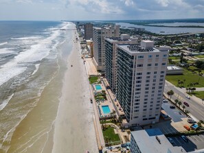 A coastal hotel with multiple high-rise buildings, a beach, and a parking area. - 🌊DiMucci Twin Towers 1402 | Pet Friendly | Sunrise + Sunset Views🏖️ (Daytona Beach)