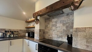 Una cocina moderna con salpicadero de piedra, techo de vigas de madera y electrodomésticos de acero inoxidable.