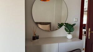 Ett rum med en rund spegel, en krukväxt, ett skrivbord och en stol.