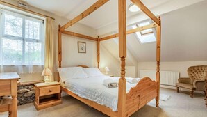 Ein Raum mit einem Himmelbett, einer Steinsäule, einem Schreibtisch und einem Stuhl.